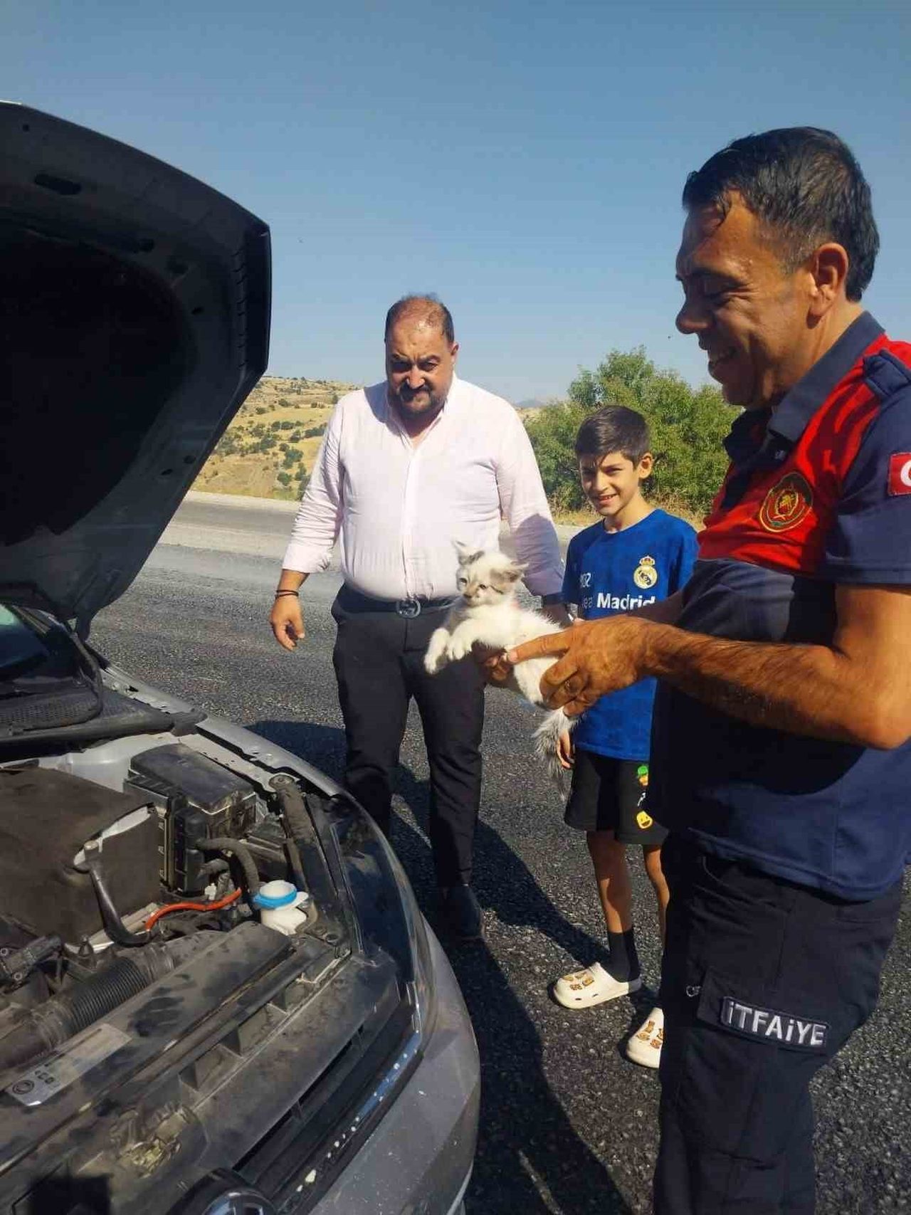 ADIYAMAN’IN BESNİ İLÇESİNDE OTOMOBİLİN MOTOR BÖLÜMÜNE GİREREK SIKIŞAN KEDİ, İTFAİYE EKİPLERİNİN...
