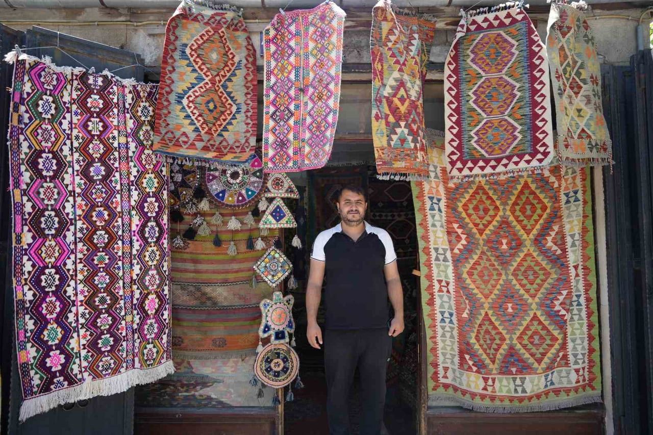 YÖRÜK KÖYLERİNDEN TOPLADIĞI HALI VE KİLİMLERİ SATARAK GEÇMİŞİ GELECEĞE TAŞIYOR
