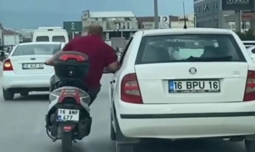 Bursa'da bir motosiklet sürücüsü arkadaşının otomobiline yaslanarak ilerledi! O anlar kameraya yansıdı